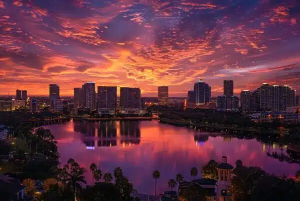 a panoramic view of a vibrant orlando skyline at sunset, showcasing a network of cloud services symbolized by luminous, ethereal wisps connecting modern skyscrapers against a backdrop of fiery oranges and deep purples.