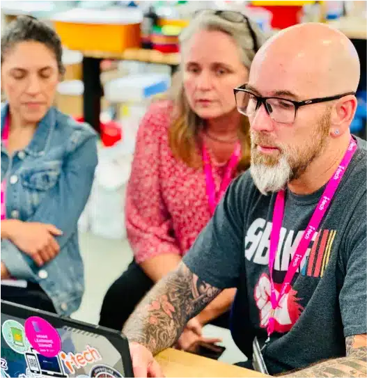 i-Tech staff and educators reviewing a laptop screen together at a school technology summit